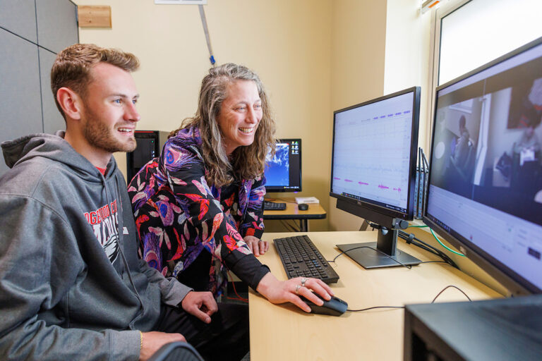 a person and person sitting at a desk with computers