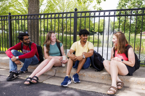 students sitting down on curb talking