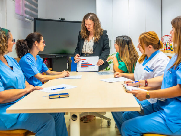 group of people sitting around table while one person is standing and presenting