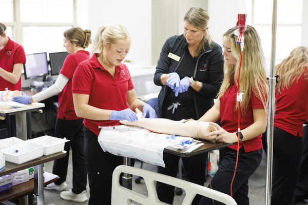 class of nursing students practicing on mannequin