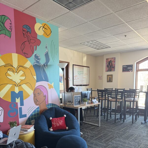 room with blue chairs, colorful painted wall, and desks