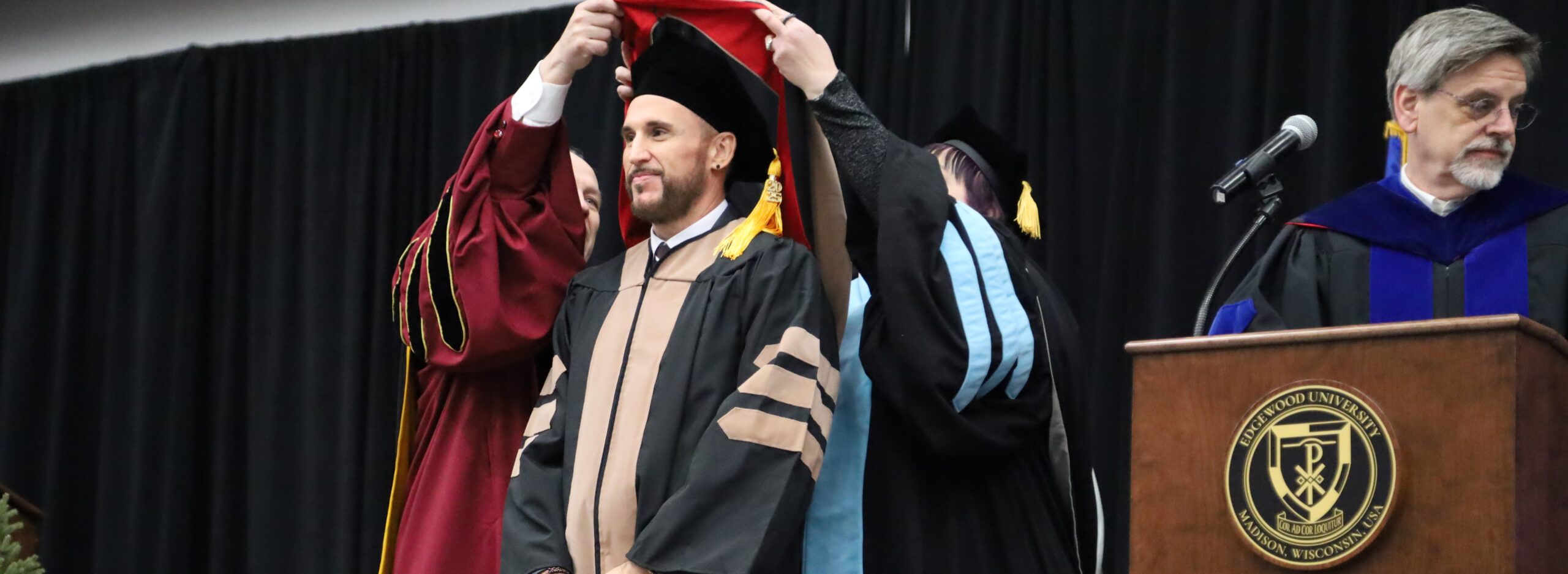man getting hooded at a graduation commencement