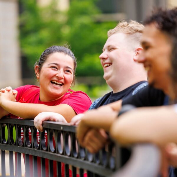 a group of people leaning on a fence